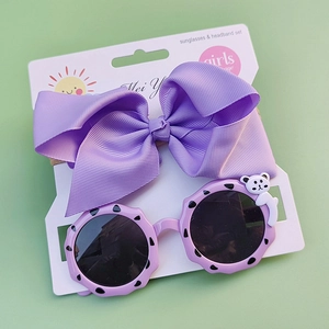 Kids purple bow headband and wave round frame sunglasses set on a white card display
