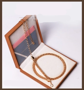 Close-up of golden textured chain belt with lobster clasp in a brown jewelry gift box