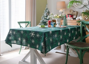 Détail d'une nappe de Noël verte avec motifs flocons blancs dans un décor chaleureux