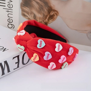 Detail of red plush headband with colorful heart patches and XOXO embroidery