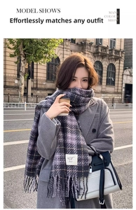 Outdoor shot of a purple plaid scarf with tassels styled with a grey coat and handbag