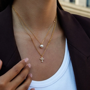 Détail d'un collier double épaisseur doré avec croix de perles et pendentif perle
