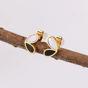 Minimalist two-tone heart stud earrings in gold and enamel on a natural branch
