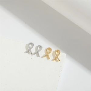 Macro detail of ribbon bow stud earrings in gold and silver finish with sparkling zircons