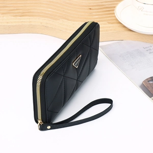 Detail of black quilted long wallet with gold zipper, fashion logo and wrist strap