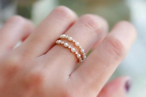 Close-up of gold-plated rings with freshwater pearls and small zirconias on fingers