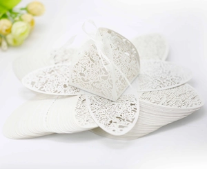 Macro detail of white hollow rose pattern wedding favor box with an elegant silk ribbon