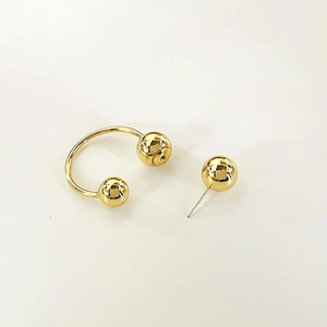 Close-up of polished gold horseshoe hoop and spherical stud earrings set on white background