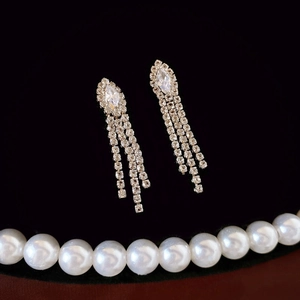 Close-up of elegant zircon tassel earrings with silver finish on dark background