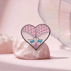 Cartoon heart-shaped enamel brooch with pink and blue colors on a mineral stone display