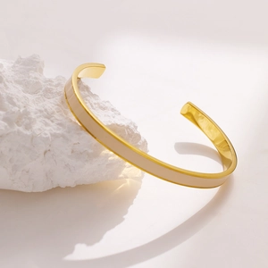 Detailansicht der goldfarbenen Edelstahl-Manschette mit cremefarbener Emaille-Einlage