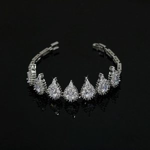Macro shot of silver wedding bracelet featuring pear-cut crystals on a black reflective surface