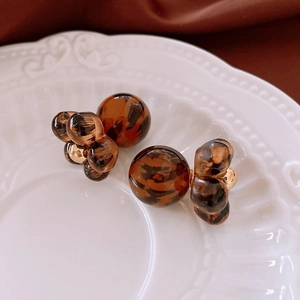Detail shot of leopard print flower earrings on a textured ceramic dish