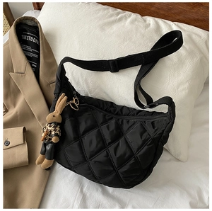 Detail of black quilted crossbody bag with rhombic stitching and cute rabbit charm