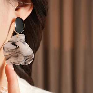 Close-up of elegant resin flower earring with black and white texture on model
