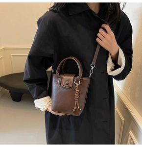 Detail of vintage brown PU leather bucket bag with braided strap and crossbody strap