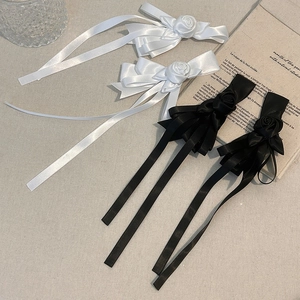 Romantic white and black rose hair clips with silk ribbons on a vintage background