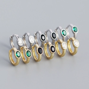 Macro view of gold and silver hoop earrings with oval zircon stones in various colors