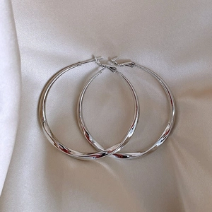 Detailed view of polished S925 sterling silver hoop earrings on elegant silk fabric