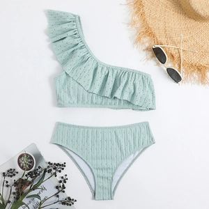 Flat lay of a mint green one-shoulder bikini with ruffle detail and summer accessories