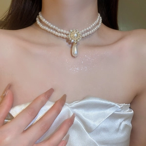 Gros plan sur un collier de perles à double rangée avec fleur en strass et pendentif goutte