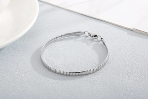 Detail of silver titanium steel chunky link bracelet with lobster clasp on a modern desk