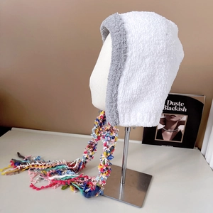 Close-up of white plush hat featuring colorful braided tassels and soft texture