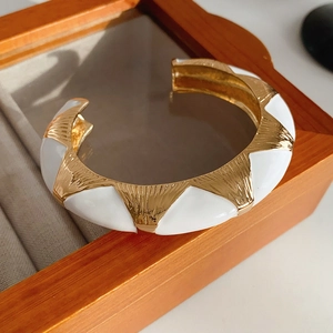Detailed macro of vintage french open bangle with gold texture and white enamel inlay