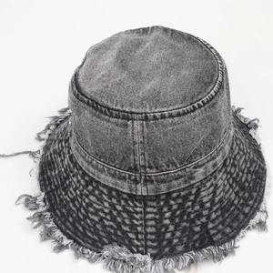 Dettaglio dei bordi sfrangiati e della trama denim lavato del cappello a secchiello