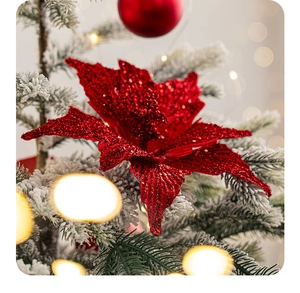 Detail of red glitter poinsettia flower on snow-covered Christmas tree branch