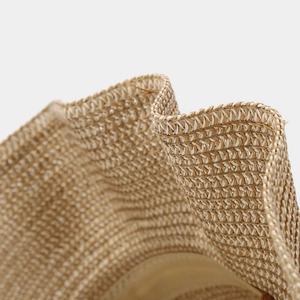 Macro detail of the woven texture and wavy edge of this beige straw cowboy sun hat