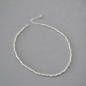 Detailed macro view of faceted silver beads and lobster clasp on a brass necklace