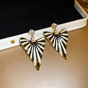 Vue macro de boucles d'oreilles triangulaires avec émail noir et blanc et plaqué or