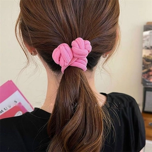 Close-up of a pink knotted elastic hair tie worn on a high ponytail for women
