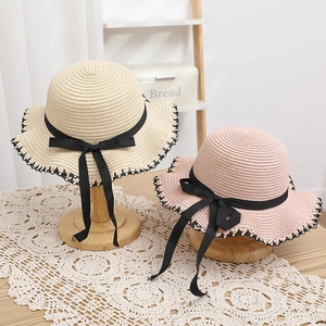 Detail of straw hat with black silk ribbon bow and delicate crochet lace edge