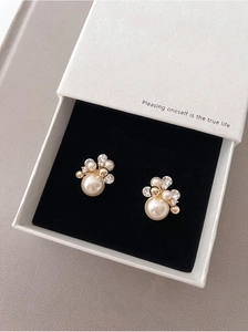 Détail de boucles d'oreilles fleurs plaquées or 18k avec perles sur velours noir