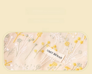 Macro detail of floral embroidery on beige linen canvas with a branded woven label