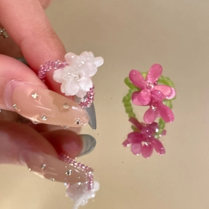 Detail of handmade beaded flower rings in pink and rose colors with mirror reflection