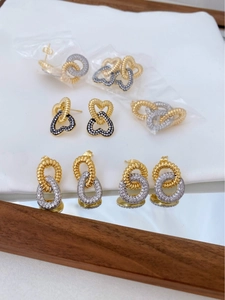 Close-up of gold-plated double-layer earrings with sparkling zircon stones on white background