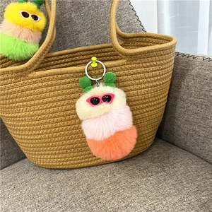 Detail van kleurrijke pluche rups sleutelhanger met bril aan een geweven tas