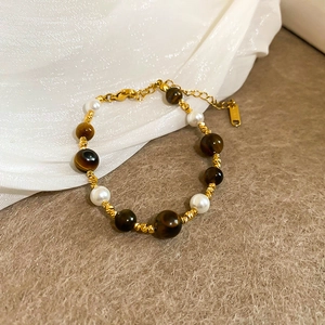 Detail of beaded bracelet with gold plating, white pearls and brown tiger eye stones