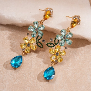 Detail of floral drop earrings with blue and yellow gemstones on a gold base
