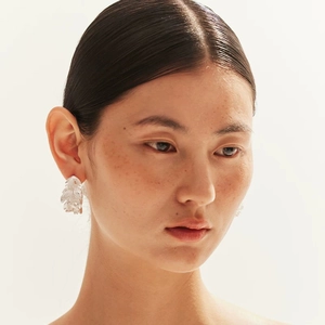 Close-up of elegant feather earrings with cubic zirconia inlay on a model ear