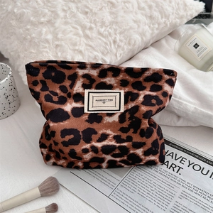 Dettaglio della borsa per trucco leopardata con etichetta su uno sfondo di peluche