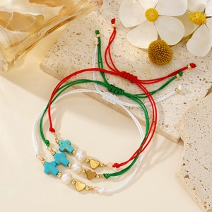 Detailed shot of cross, pearl, and heart charms on colorful braided cord bracelets