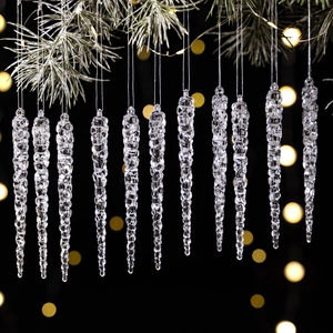 Close-up of 12 transparent acrylic icicle ornaments hanging from green pine branches
