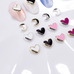 Macro shot of silver heart and moon metal nail charms with enamel finish and Sweet text