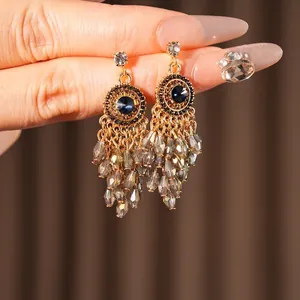 Bohemian gold tassel earrings with blue gemstone and grey faceted beads on hand