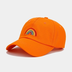 Close-up of rainbow embroidery detail on orange cotton baseball cap with curved brim