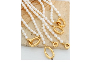 Detail of freshwater pearl necklace with irregular gold metal clasp on stone